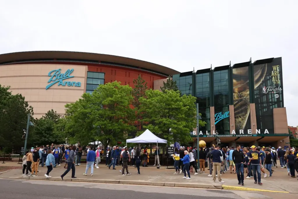 Evening traffic and crowds gathering outside Denver Ball Arena before show.