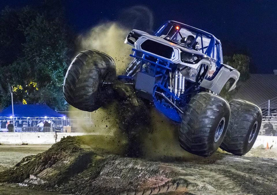 Monster trucks racing and jumping during daytime and nighttime Pueblo shows.