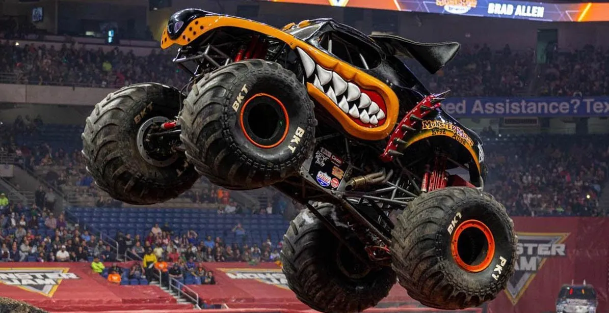 A monster truck flying through the air in front of a crowd